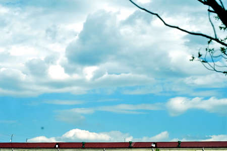 white clouds in the bright sky over the city roofsの写真素材