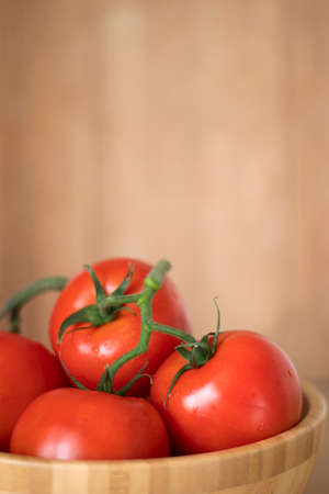 red tomatoes with a wooden bowl close-upの写真素材