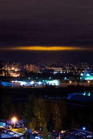 Night landscape of a residential area on the outskirts of a megalopolis in Russia, with the sky illuminated by the light of the centeの写真素材