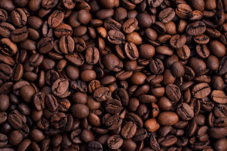 Scattered piles of roasted arabica coffee beans top view close up in daylightの写真素材