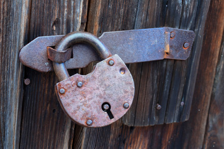 Old rusty padlock on an old wooden door, close-up