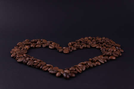 Big heart of coffee beans on a dark surface