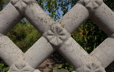 a section of a gray cement and sand fence is shown close with a pattern in the rays of lightの写真素材