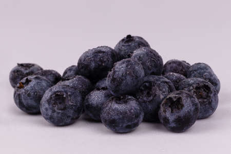 Side close view of a pile of wet blueberries on white background laying together