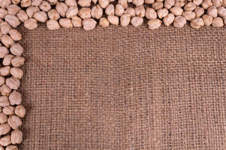 A half of a frame around the photo made of dry chickpeas scattered on textured textileの写真素材