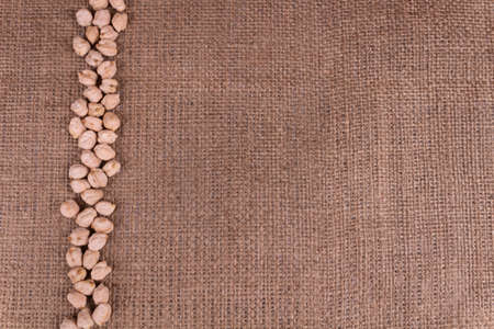 A line made of chickpeas dry beans laying on textures sackclothの写真素材
