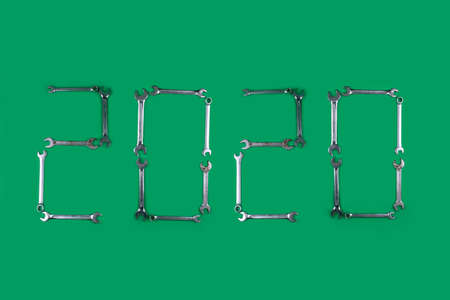 A year 2020 made of small wrenches laid out on a green backgroundの写真素材