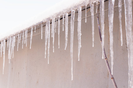 Many long and short icicles on the edge of the roof