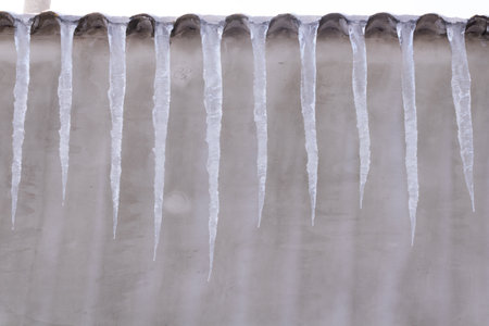 An even row of medium icicles hanging from the roof