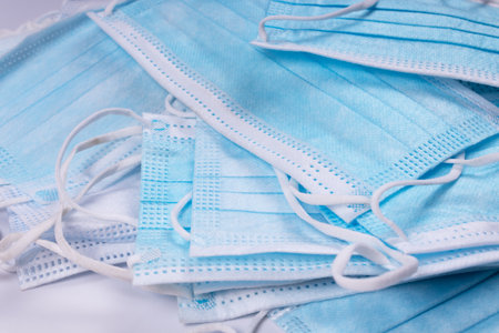 angled view of blue medical masks piled in a pile