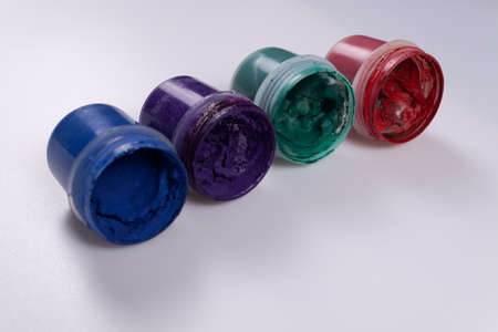 blue, orange, green and red cans of gouache paint lie on the side diagonallyの写真素材