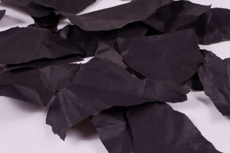 torn pieces of black crumpled paper piled up in a heap side angle viewの写真素材
