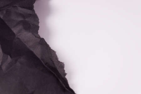 on the left side of the frame, torn off at the edge, wrinkled black paperの写真素材