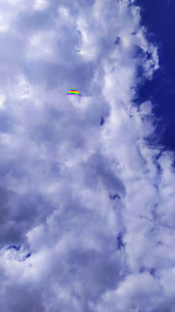 the blue sky is almost completely covered with white clouds with a colored kite