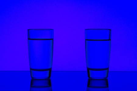 two glasses are isolated on a blue backgroundの写真素材