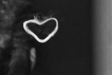 Ring out of steam in the shape of a heart from e-cigarette for background. Vaping. Black and white photo.の写真素材
