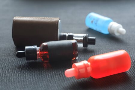Vape. Bottle with e-liquid and nikotine and electronic cigarette mod on black textile. Personal vaporizer.の写真素材