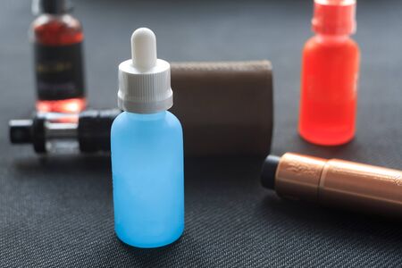 Vape. Bottle with e-liquid and nikotine and electronic cigarette mod on black textile. Personal vaporizer.の写真素材
