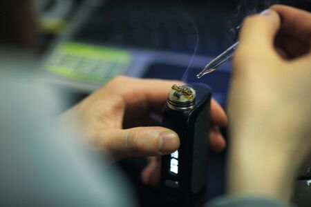Vape after-sales service of the electronic cigarette. Male hands add liquid with nicotine for vaping. ENDS. Close up.の写真素材