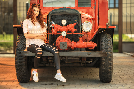 Vintage firefighting truck and pretty teenager. Outdoor portrait of a beautiful young white girl...