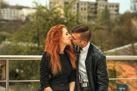Kiss. Couple in love. Handsome guy and pretty girl posing on the modern urban car parking.の写真素材