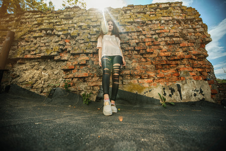 Beautiful teenager. Outdoor portrait of a pretty young white girl with red curly hair posing near old destroyed red brick wall. Lifestyle.の写真素材