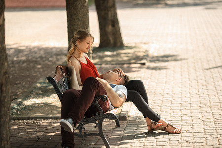 Young modern couple falling in love on the bench at summer day.の写真素材