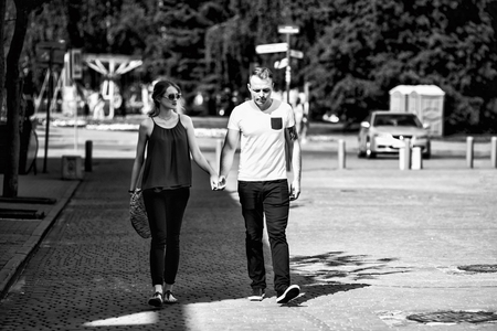 A loving couple strolls along a city street on a sunny summer day. Young boy and girl. Black and white photo.の写真素材