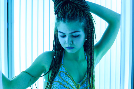 Solarium. Young pretty girl with african braids in a dress for oriental dances sunbathing in a...
