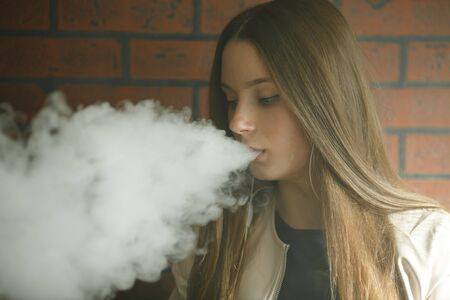 Vaping teenager. Young pretty white girl smoking an electronic cigarette in vape bar. Bad habit.