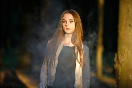 Vape teenager. Young cute girl in casual clothes smokes an electronic cigarette outdoors in the...
