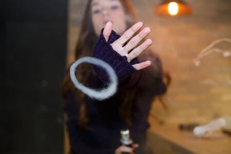 Vaping teenager. Young pretty white girl smoking an electronic cigarette in vape bar. Bad habit. Close up.の写真素材