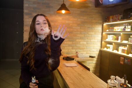 Vape teenager with problem skin. Young pretty white girl smoking an electronic cigarette in vape...