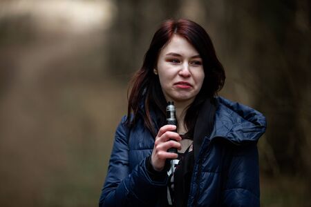 Vape teenager. Young pretty caucasian brunette girl with problem skin smoking an electronic...