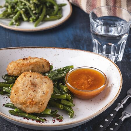 Delicious chopped chicken steak with beans on a plate. Chicken cutlet with garnish.