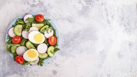 Top view of healthy salad with eggs and fresh vegetables on a plate over gray background. Copy spaceの写真素材