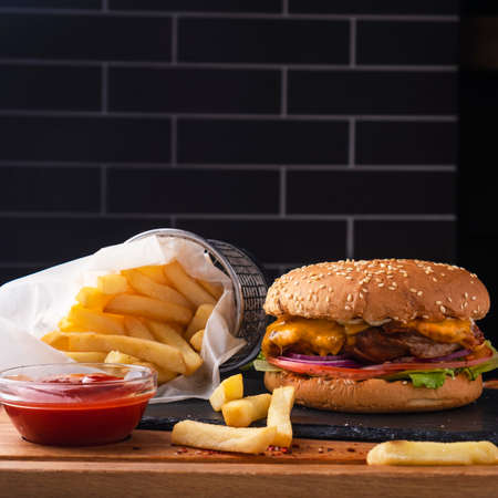 Delicious fast food burger with meat, onion, cheese and lettuce garnish with french fries and ketchup. Copy spaceの写真素材