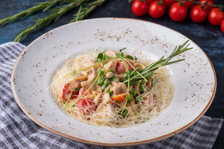 Delicious spaghetti with chicken, vegetables and cheese on a plate.の写真素材