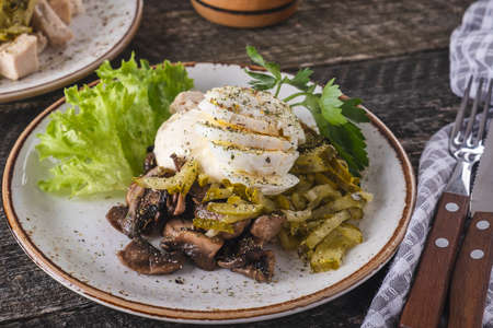 Delicious salad with chicken fillet, mrinated cucumbers, mushrooms and eggs served with fork and knifeの写真素材