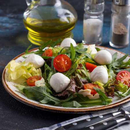Delicious vegetarian salad with arugula and fresh vegetables on a plate. Healthy food concept. Closeupの写真素材