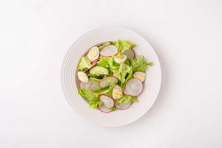 Healthy vegetables salad with cucumbers, quaill eggs and radish. Fresh vegetables salad isolated on white background. Top view, text spaceの写真素材