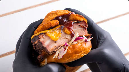 Hands in black gloves hold meat burger