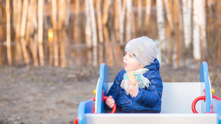 Little boy sitting on a swing and eating ice cream. Copy spaceの写真素材