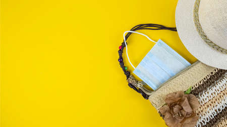 Beach hat, bag and protection mask on yellow background. Top view, text spaceの写真素材