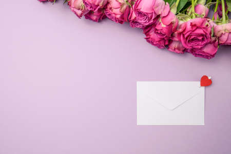 Envelope and rose flowers on violet background. Valentine's day concept. Top view, copy spaceの写真素材