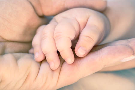 Mother holds newborn baby hand. Care concept. Toned photoの写真素材