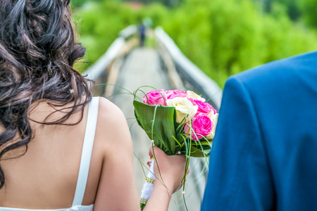 Young couple walking on wooden bridge with the wedding bouquet summerの写真素材