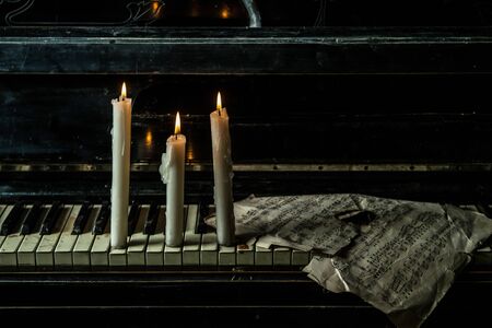 Candles are lit on the piano with music sheetsの写真素材