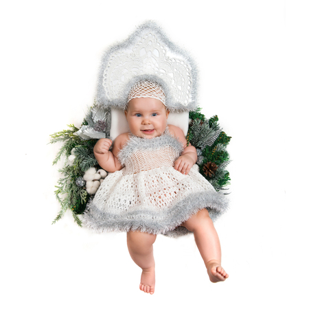 Little girl lying on the Christmas wreath in a white knitted dress and headdressの写真素材