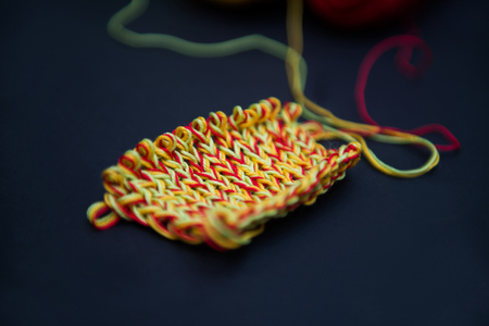 a piece of knitting on a black background, red, yellow, green